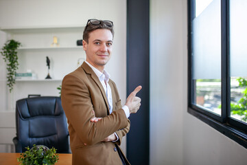 young businessman standing near window in office - 553006387