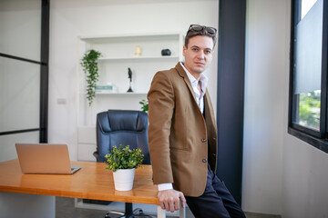 young businessman standing near window in office - 553006397
