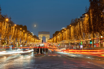 Fototapeta na wymiar Paris - France,France - 12 08 2022: View of the Arc-De-Triomphe and Avenue des Champs Elysees with Christmas lights and full moon