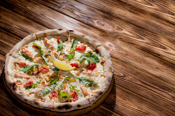 Pizza with salmon, mozzarella, cherry tomatoes, arugula, lemon and parmesan. Italian cuisine on a...