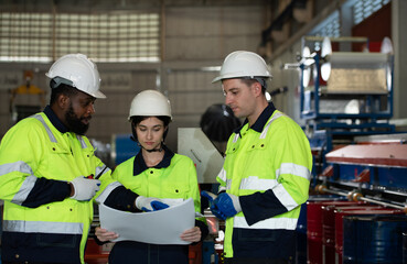Young female engineer learning to run machinery at a factory with veteran engineers