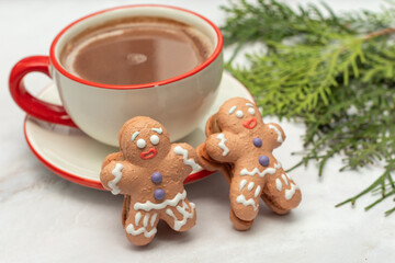 Hot winter drink - chocolate in white mug with gingerbread man. Christmas time. Cozy home atmosphere, white background. Holiday mood in the air