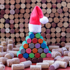 Colorful painted wine cork Christmas tree in Santa hat among used wine corks