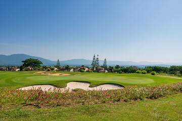 Sand by flagstick on the fairway of a golf course near houses in valley
