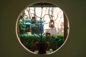 Dead tree on flower pot with hanging lamps by circle window