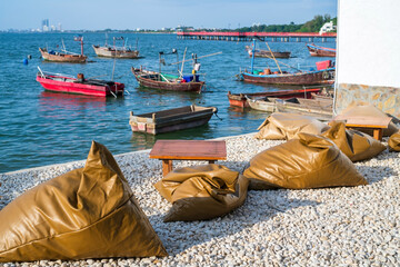 Brown beanbags on white rocks by sea with wooden fishing boats