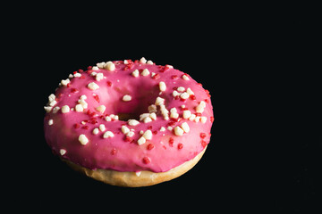 Close-up, pink donut on a black background.