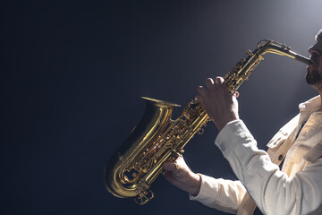 A European man plays the saxophone in the dark. - obrazy, fototapety, plakaty