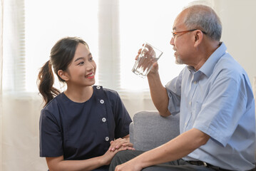 Asian caregiver helping senior man eat medicine