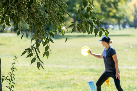 Woman playing flying disc golf sport game in the park