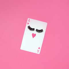 Ace of hearts card with false eyelashes, creative love game layout against hot pink leather texture background. 