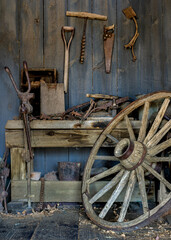 Blacksmith workshop with bench and wooden wheel against wooden blue wall