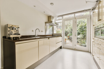 a modern kitchen with white cabinets and black counter tops in an open doord area that leads to the...