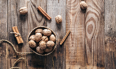 Bowl with whole walnuts on wooden background, flat lay.