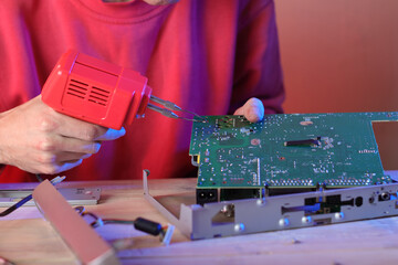 soldering the motherboard with a transformer soldering iron by a person