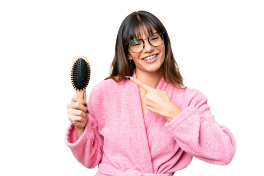 Young woman with hair comb over isolated chroma key background and pointing it