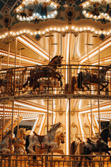 Golden magic retro children's carousel with horses Merry-go-round in the fairy garland bokeh lights. Vertical postcard