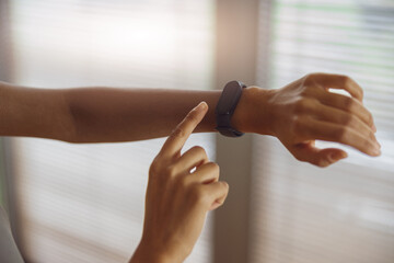 Close up of woman looking at sports watch and checking her performance after exercise at home