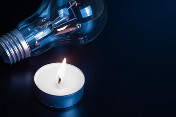 Electric lamp and candle on a dark background. Incandescent lamp and candle. No or power outage....