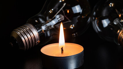 Electric lamp and candle on a dark background. Incandescent lamp and candle. No or power outage....