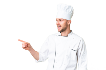 Young caucasian chef over isolated chroma key background pointing finger to the side and presenting a product