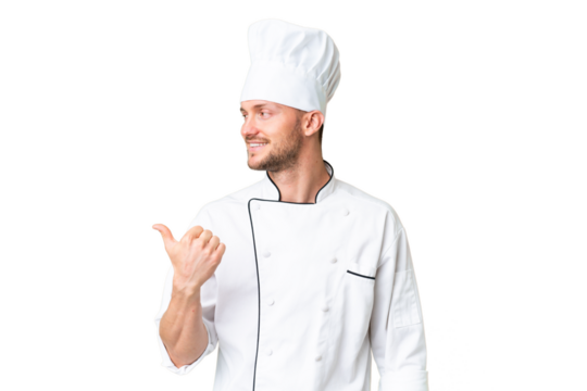 Young caucasian chef over isolated chroma key background pointing to the side to present a product