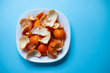 Top view of mandarin peel on plate on blue background