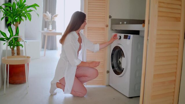 Beautiful cute satisfied happy smiling joyful housewife woman doing laundry at home