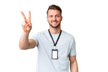 Young caucasian man with ID card over isolated chroma key background smiling and showing victory sign