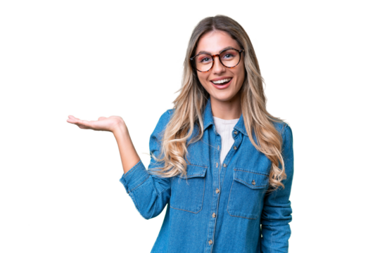 Young Uruguayan woman over isolated background holding copyspace imaginary on the palm to insert an ad