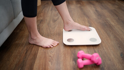 Woman leg stepping on scales at home. Measurement instrument in kilogram for diet Lose weight...