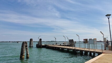 Sea view, wooden bridge and pillars at the sea pier, Venice, Italy