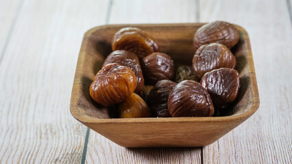 Castañas naturales peladas y hervidas , detalle de primer plano sobre un cuenco de madera de caoba 