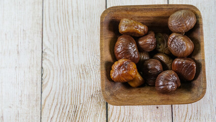 Castañas naturales peladas y hervidas , detalle de primer plano sobre un cuenco de madera de caoba 