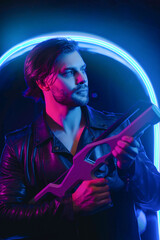 Handsome man in cyberpunk style with a machine gun in his hands in the dark. A guy in a leather jacket in the scenery of the future in neon color. Spaceship.