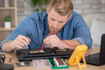 technician using multimeter to analyse and repair laptop computer