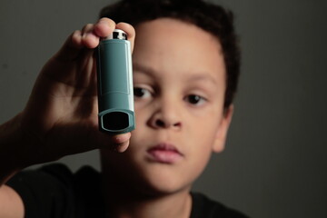 child with flu with inhaler on grey background with people stock photo