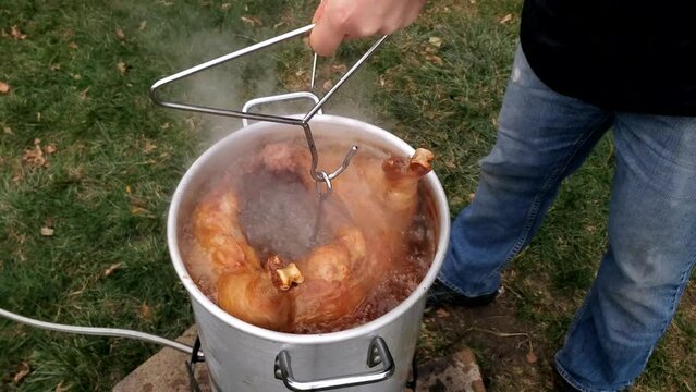 Checking temp and tenderness of large whole Turkey while being deep fried in large pot. 