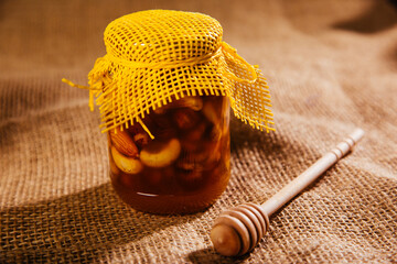 A jar of honey with assorted nuts. Useful product of beekeeping.