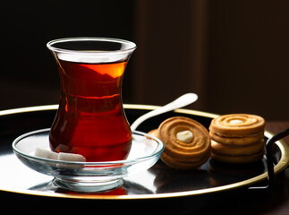 Turkish Tea presentation with biscuit on tray. Tea time for Turkish people. Turkish Tea in traditional glass on sunset time. .