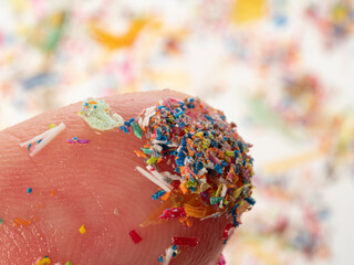 Microplastics in water - polluted water - macro photography of finger with microplatics peaces