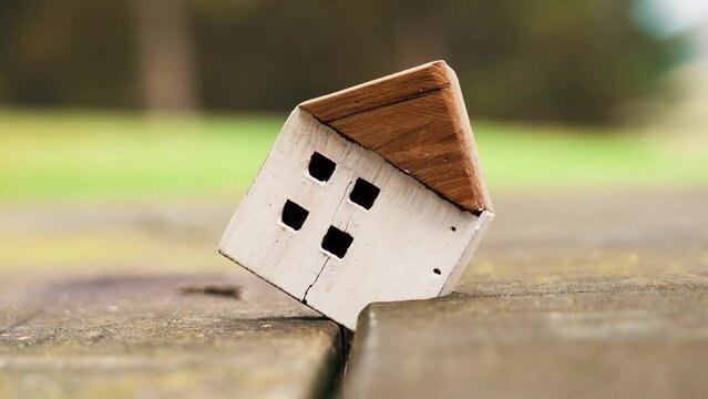 Wooden cracked house model in a board fracture outdoor. The concept of disaster real estate insurance. Housing crisis. Close up