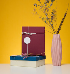 A stack of gift boxes wrapped in colorful paper on a yellow background. Happy Holidays