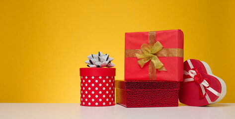 A stack of gift boxes wrapped in colorful paper on a yellow background. Happy Holidays