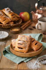 Hand pies. Mini puff pastry or hand pies stuffed with apple and sprinkle sugar powder in wooden plate. Homemade pie snack with crust for breakfast rustic photo.  Copy space.