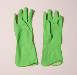 Pair of green protective rubber gloves for cleaning on a beige background