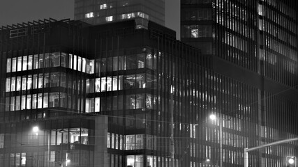 Pattern of office buildings windows illuminated at night. Glass architecture ,corporate building at night - business concept. Black and white.