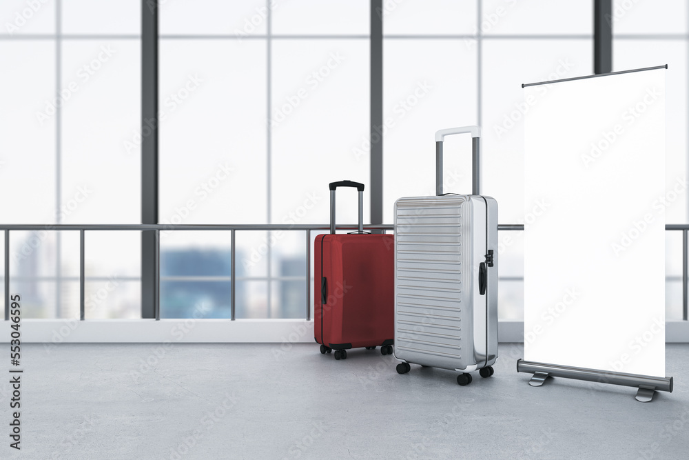 Poster empty white roll-up mock up poster, red and gray suitcases placed in modern blurry airport interior 