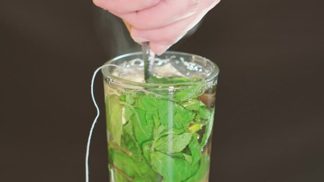 moving spoon in a clear cup of thea with mint