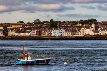 Traditional fishing boat in the harbor of Portaferry. Colorful houses next to the sea on the background. Strangford Lough, Northern Irland, UK